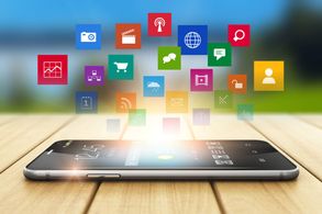 iPhone on a table with social media icons hovering above it.